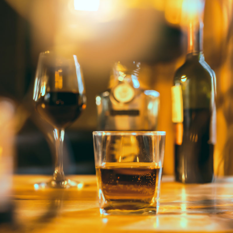 A glass of whiskey and a bottle of fine red wine